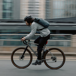 Man wearing The Roll Top 20L backpack in Tasmin Blue on a bike