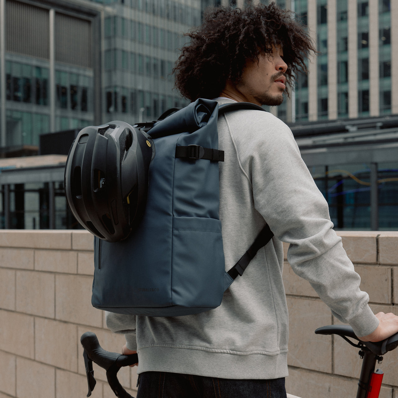 Man wearing The Roll Top 20L backpack in Tasmin Blue on a bike