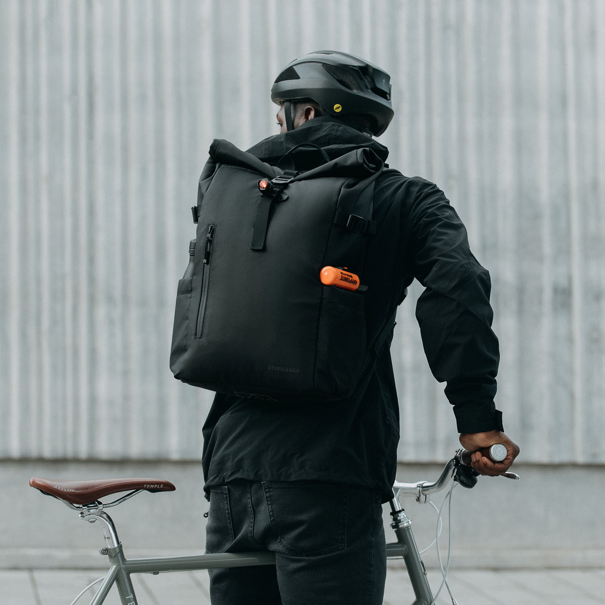 Cyclist in a helmet with a bike, wearing The Roll Top 20L in All Black