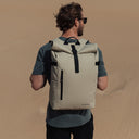 Man wearing The Roll Top 20L backpack in Sand on a beach