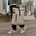 Man carries The Roll Top 20L backpack in Sand