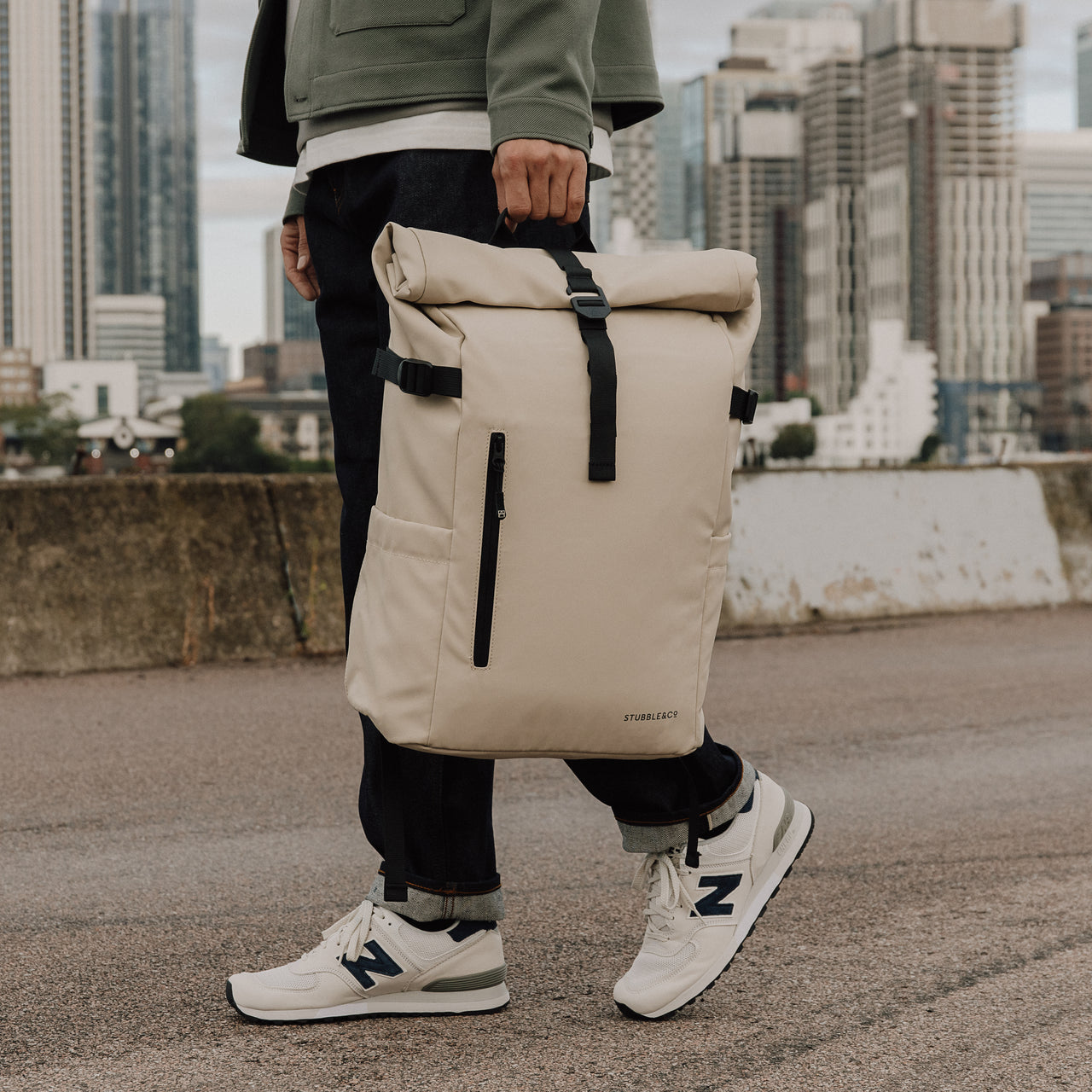 Man carries The Roll Top 20L backpack in Sand