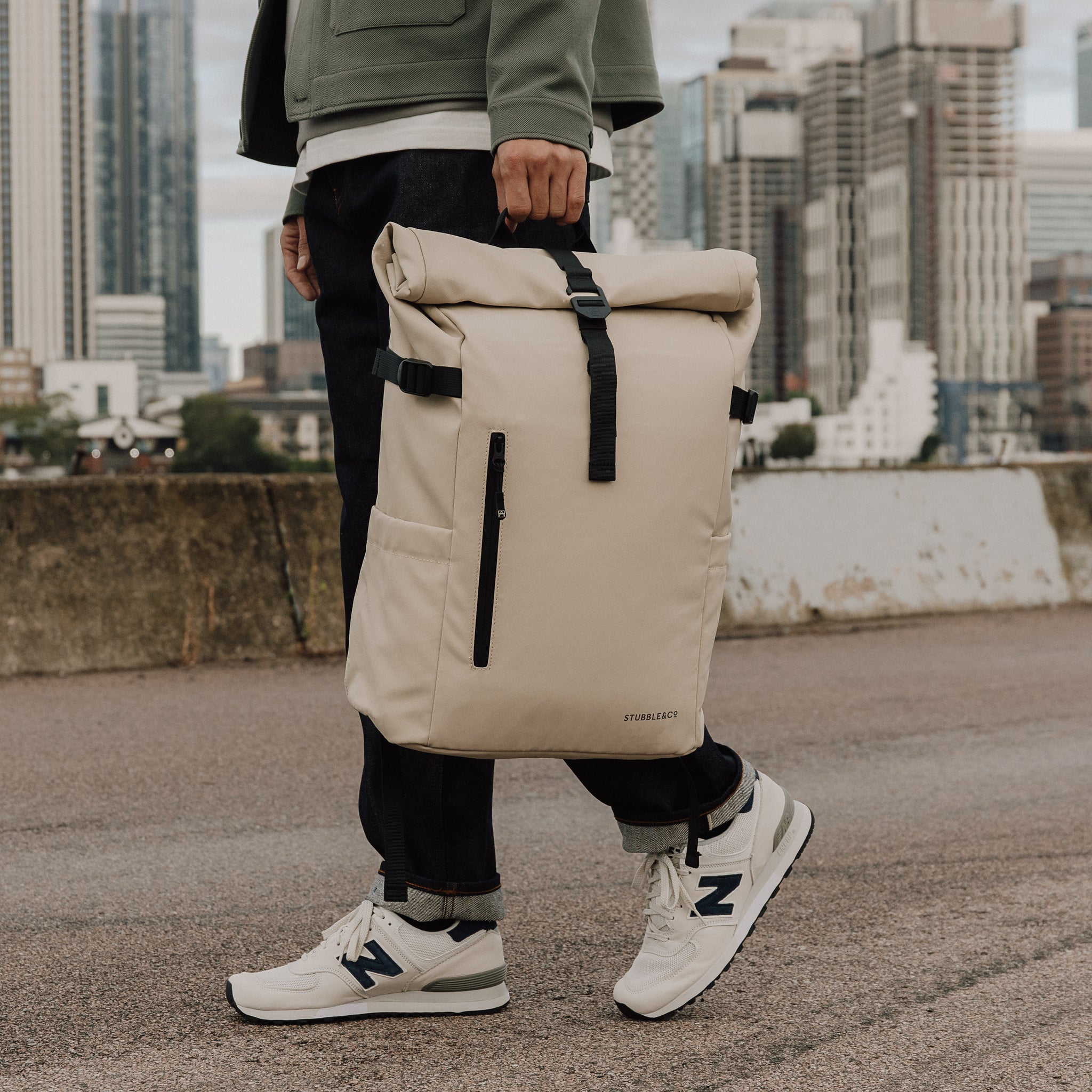 Man carries The Roll Top 20L backpack in Sand