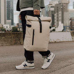 Man carries The Roll Top 20L backpack in Sand