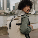 Man wearing The Roll Top 20L backpack in Sand