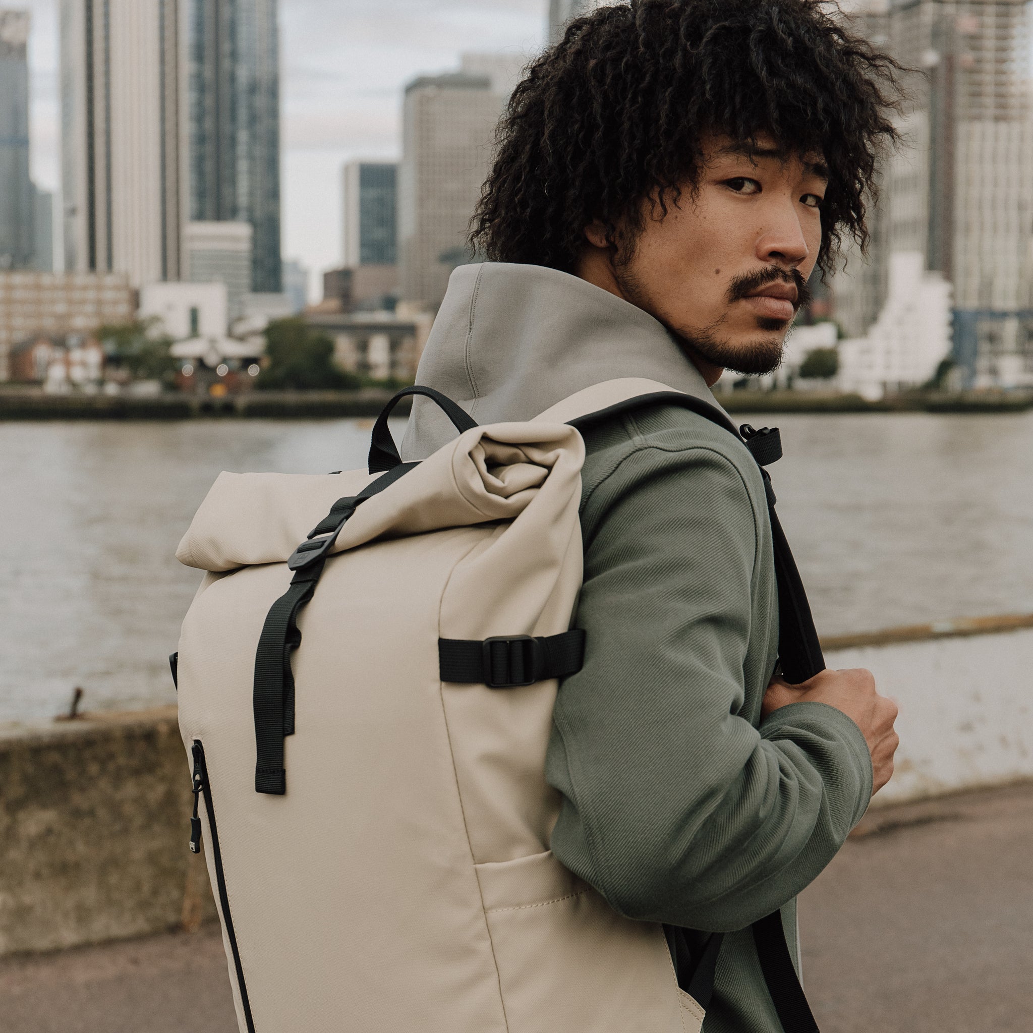 Man wearing The Roll Top 20L backpack in Sand