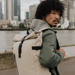 Man wearing The Roll Top 20L backpack in Sand