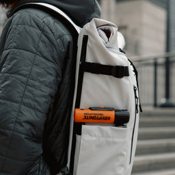 Close up of person wearing The Roll Top 20L in Arctic White with a bike lock in the pocket
