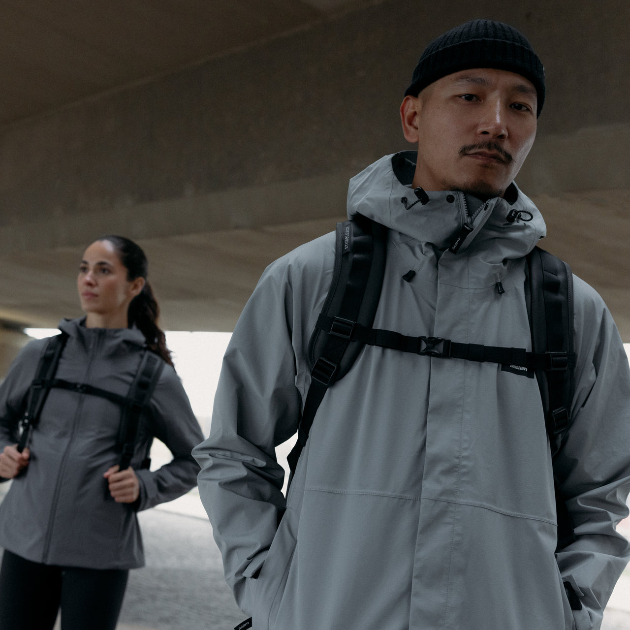 A man and woman wearing Roll Top backpacks with the chest strap done up in All Black