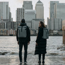 Man and women wearing the Roll Top 15L in Concrete standing by the edge of a river in a city