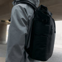 A close up of the laptop pocket on the Roll Top 20L in All Black with a man wearing it on his back 