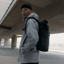 A man wearing a Roll Top 20L on his back in All Black
