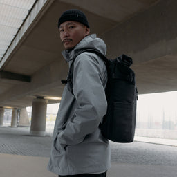 A man wearing a Roll Top 20L on his back in All Black