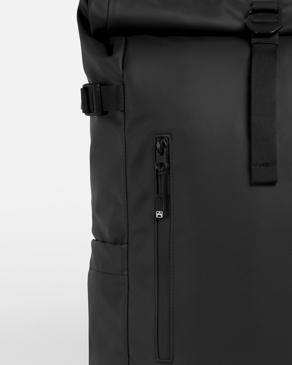 Close up of zip pocket on the front of a Roll Top backpack in black