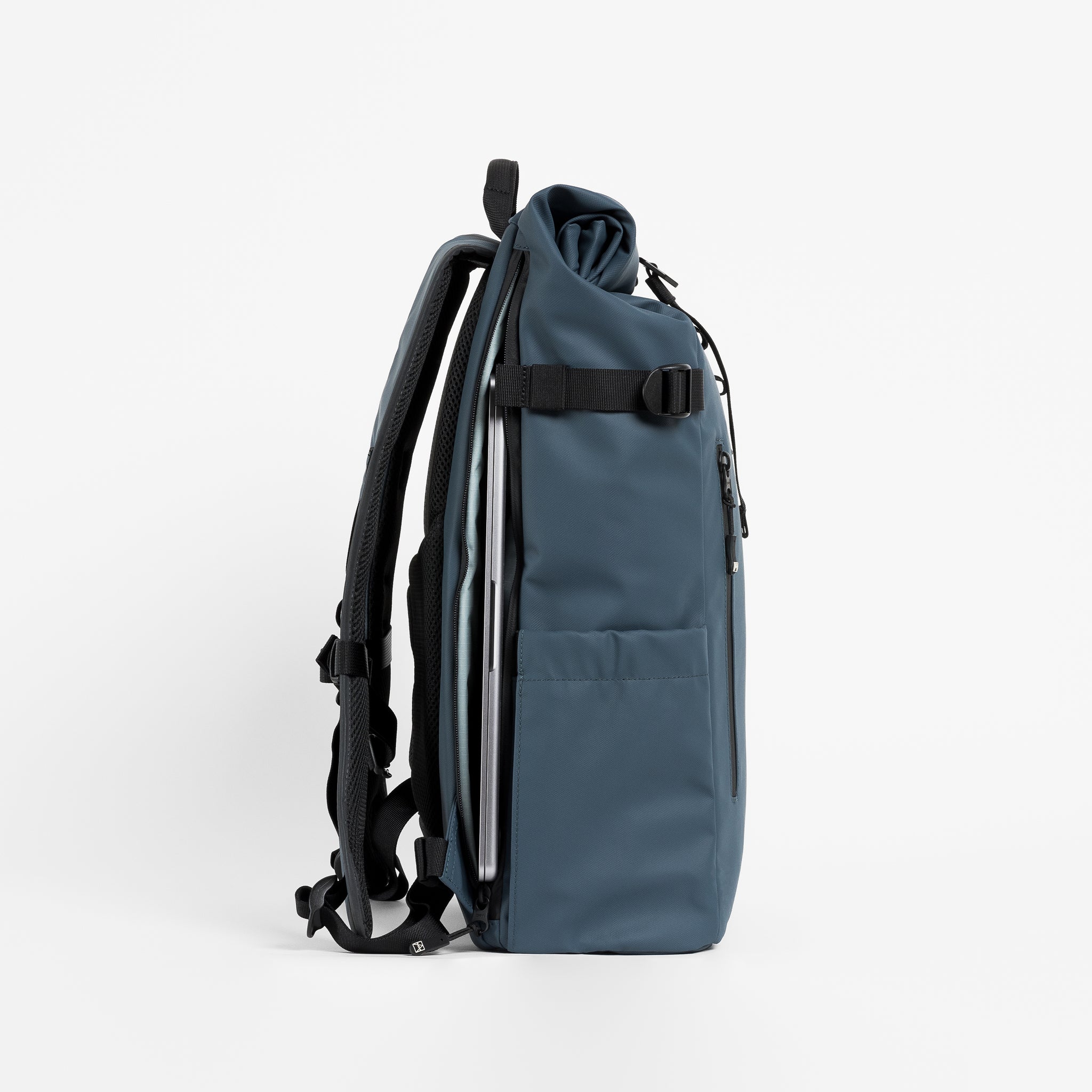 Side view of The Roll Top 20L backpack in Tasmin Blue with laptop compartment