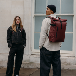A man and woman wearing Roll Top 20L on their back in Garnet Red