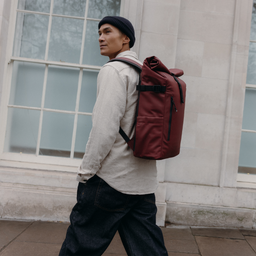 A man walking wearing a Roll Top 20L in Garnet Red on his back