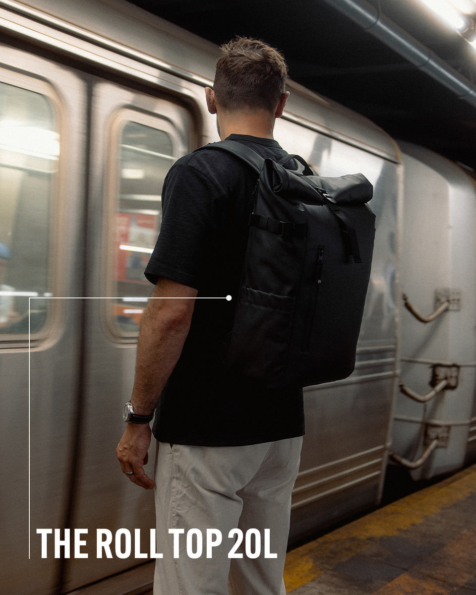 a man waiting on the subway platform wearing a roll top 20l with product name annotated
