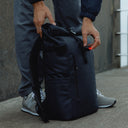 A man clipping on a bike light onto a Roll Top 20L in Midnight Blue