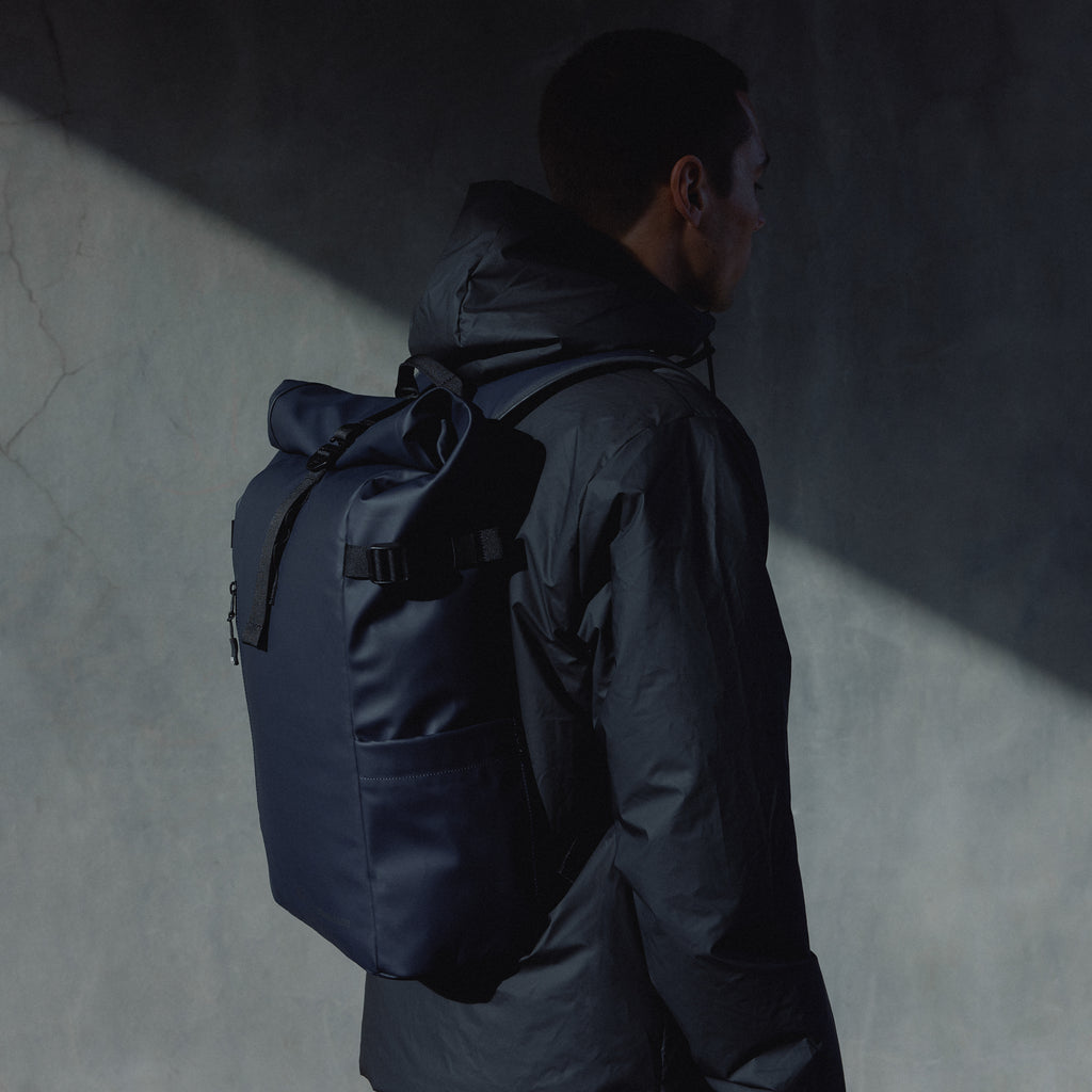 A man wearing a Midnight Blue Roll Top 20L on his back