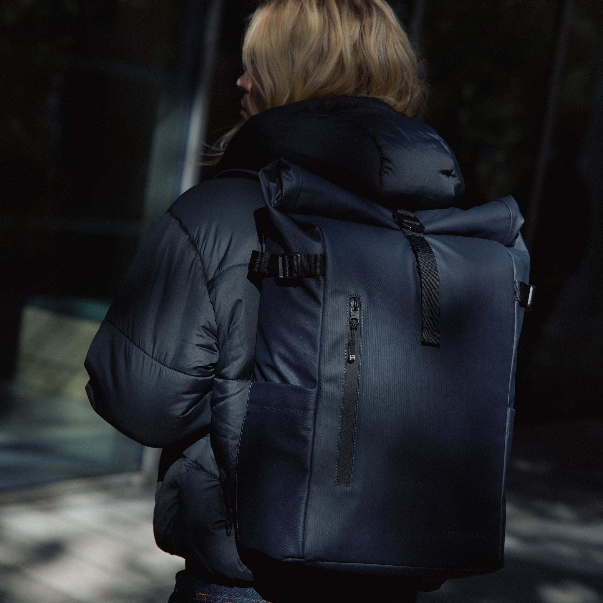 A woman wearing a Roll Top 20L in Midnight Blue on her back