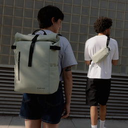 A woman wearing a Roll Top 20L in Soft Mint on her back with a man wearing a crossbody next to her