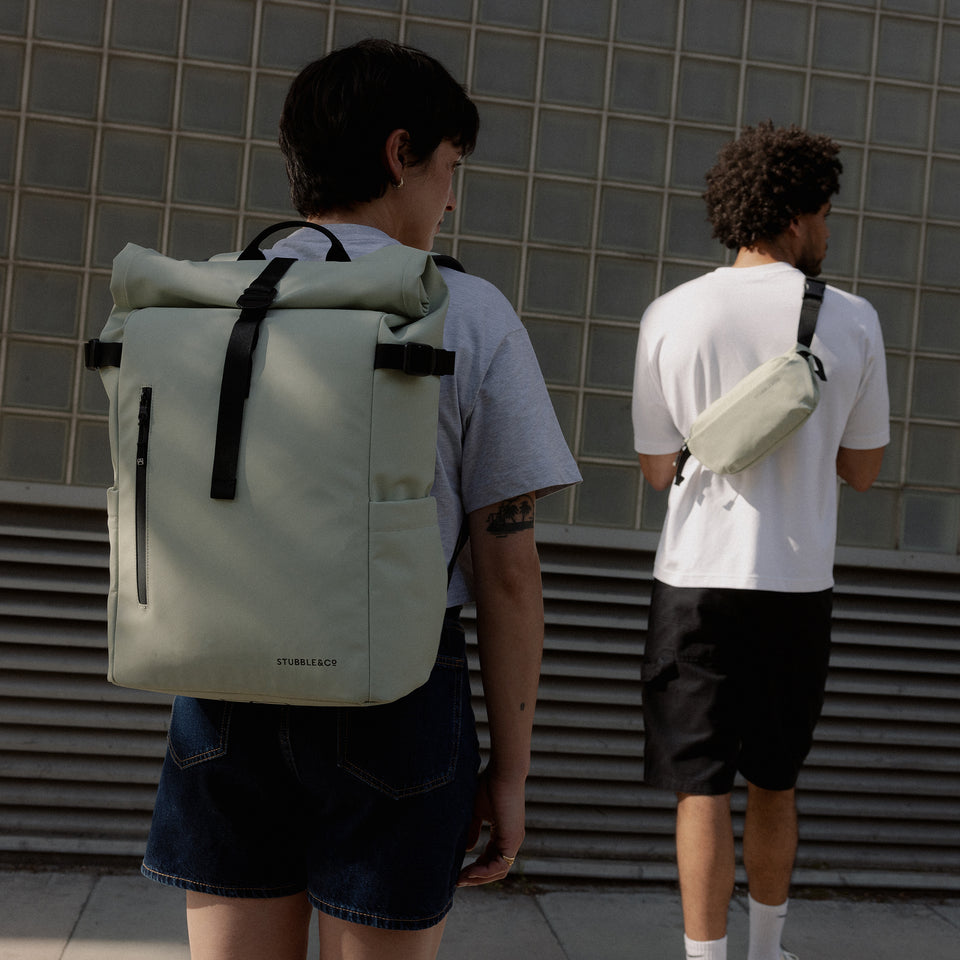 A woman wearing a Roll Top 20L in Soft Mint on her back with a man wearing a crossbody next to her