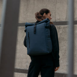 A woman wearing a Roll Top 20L in Tasmin Blue on his back