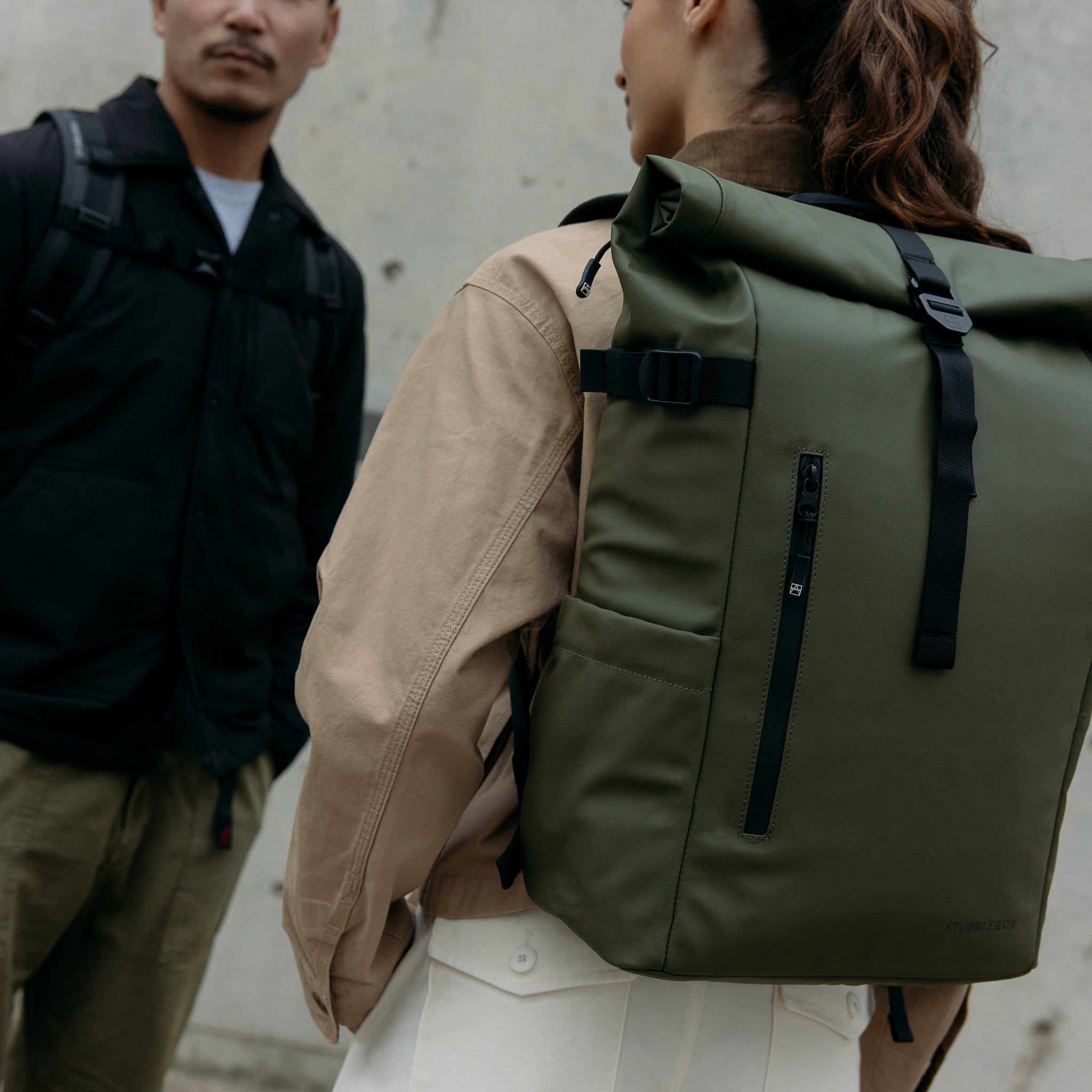A close up of a Roll Top 20L backpacks in Urban Green on a woman's back