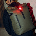 A close up of the Roll Top 20L backpack in Urban Green in the rain showing the waterproof materials and bike light attached