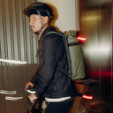 A man walking with his bike wearing a helmet and Urban Green Roll Top 20L backpack on his back