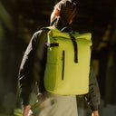 A woman wearing a Roll Top 20L in Volt on her back