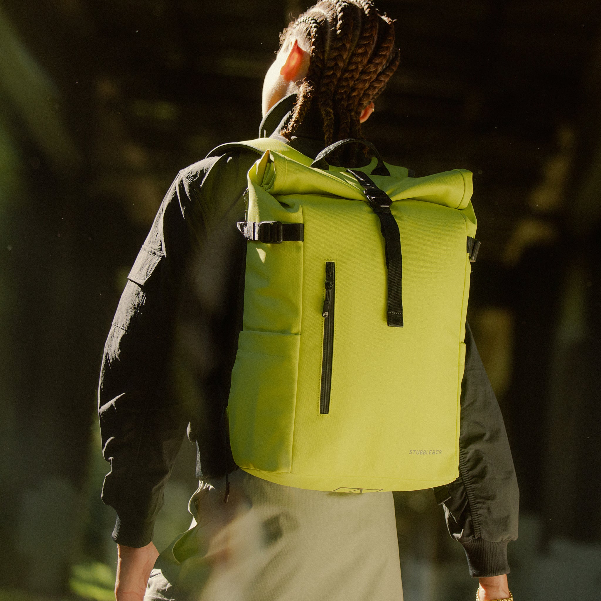 A woman wearing a Roll Top 20L in Volt on her back