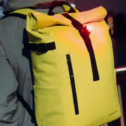 A close up of Volt Roll Top 20L on a mans back with a bike light attached to the G-Hook