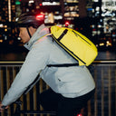 A man cycling along the river side with a Roll Top 20L Volt on his back