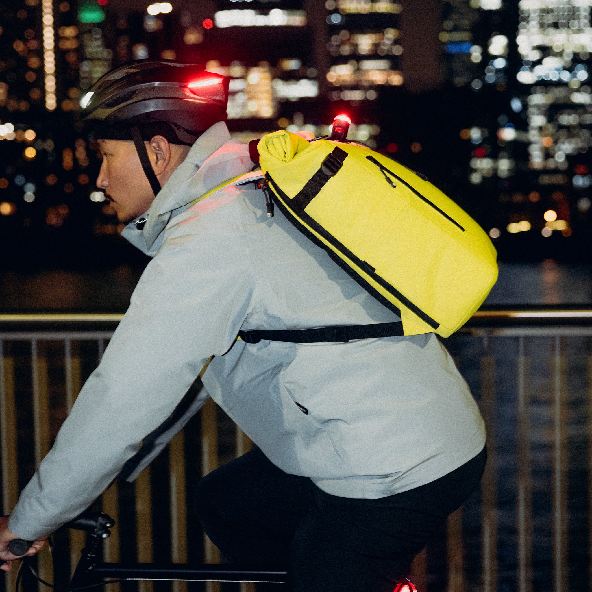 A man cycling along the river side with a Roll Top 20L Volt on his back
