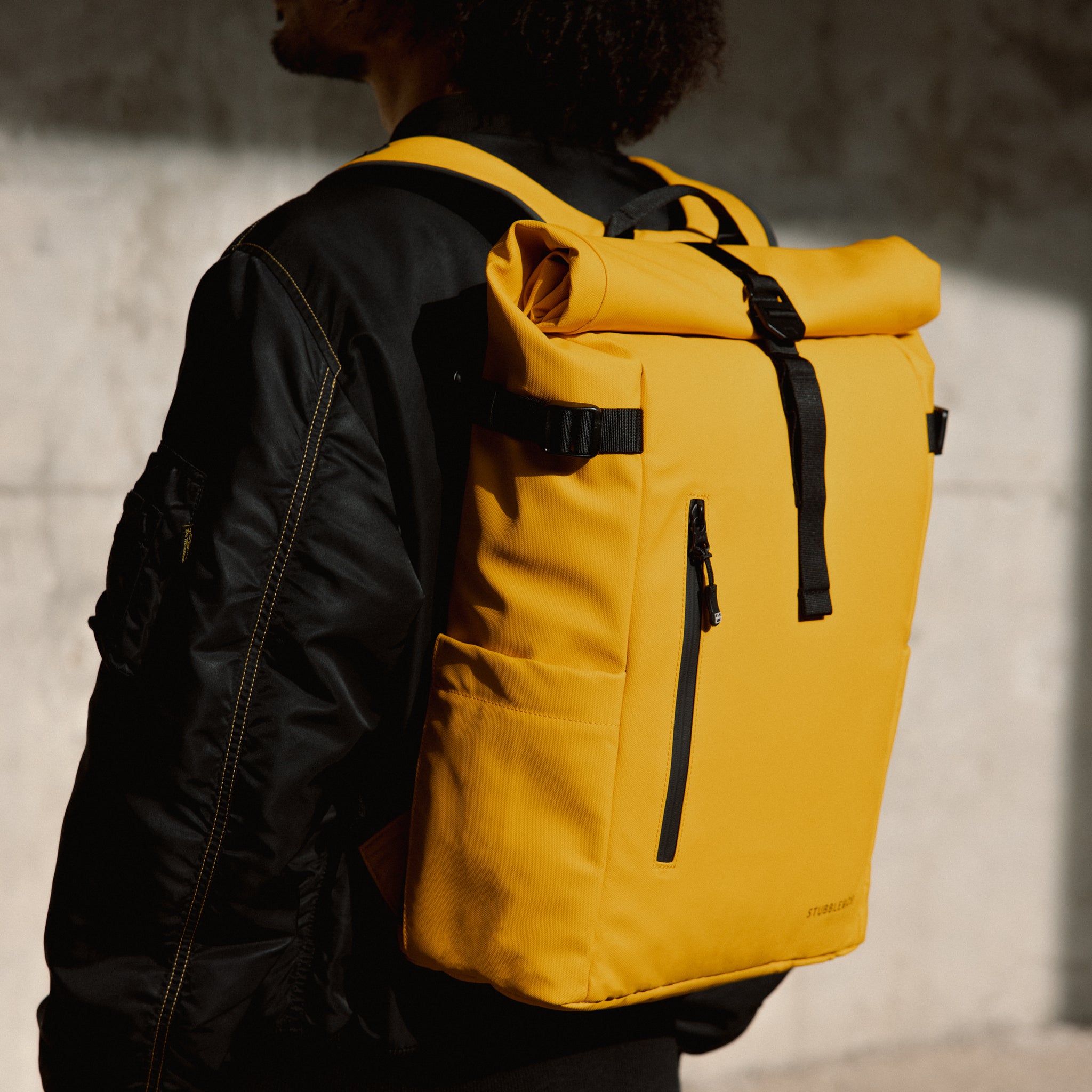 a close up of a Yellow roll top 20l on a mans back