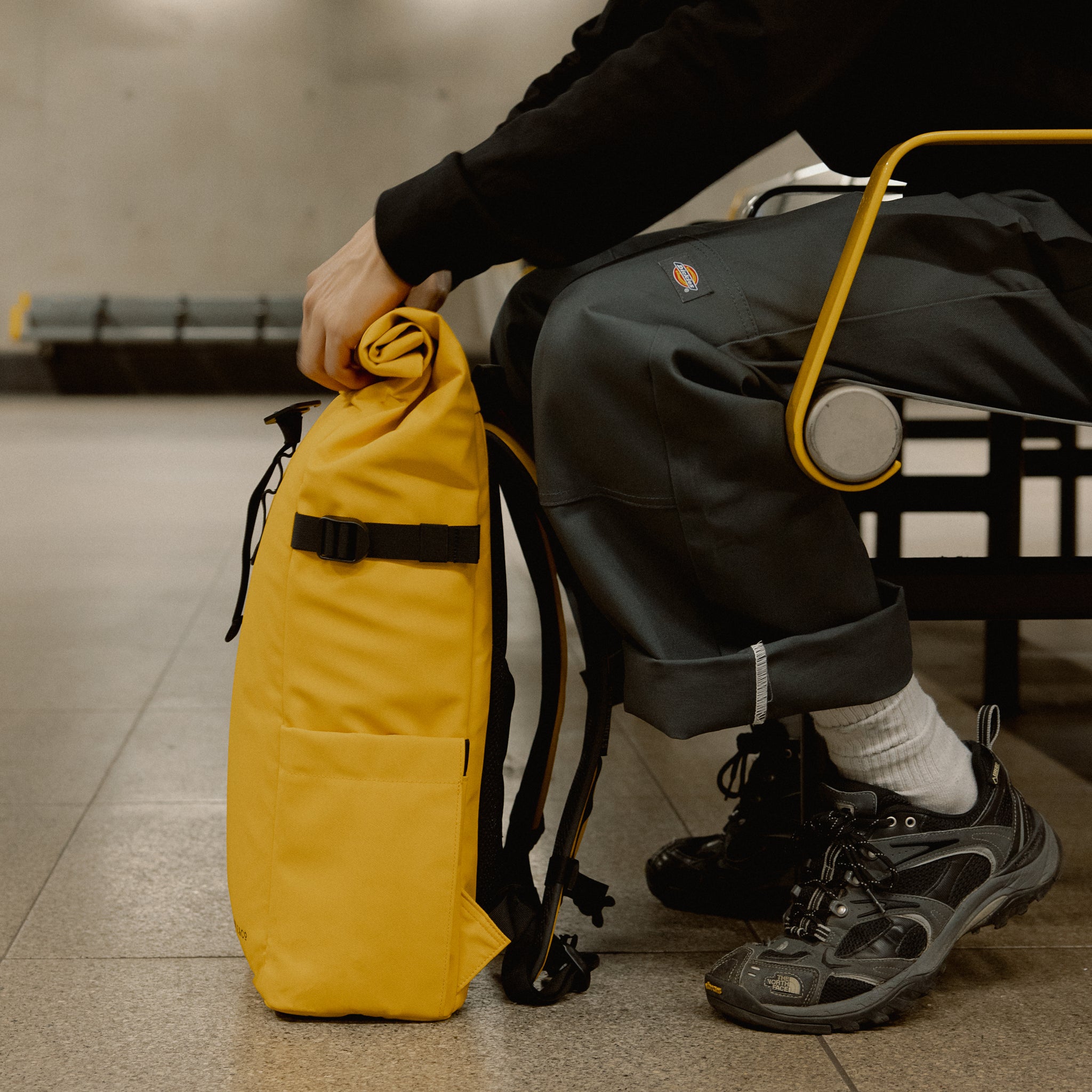 a close up of the side of a Yellow roll top 20l whilst a man rolls the top