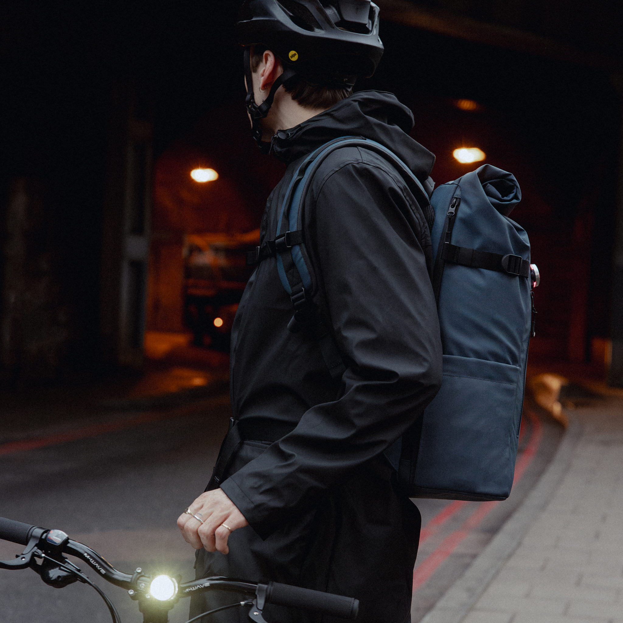 A man standing next to his bike with a Roll Top 30L in Tasmin Blue on his back