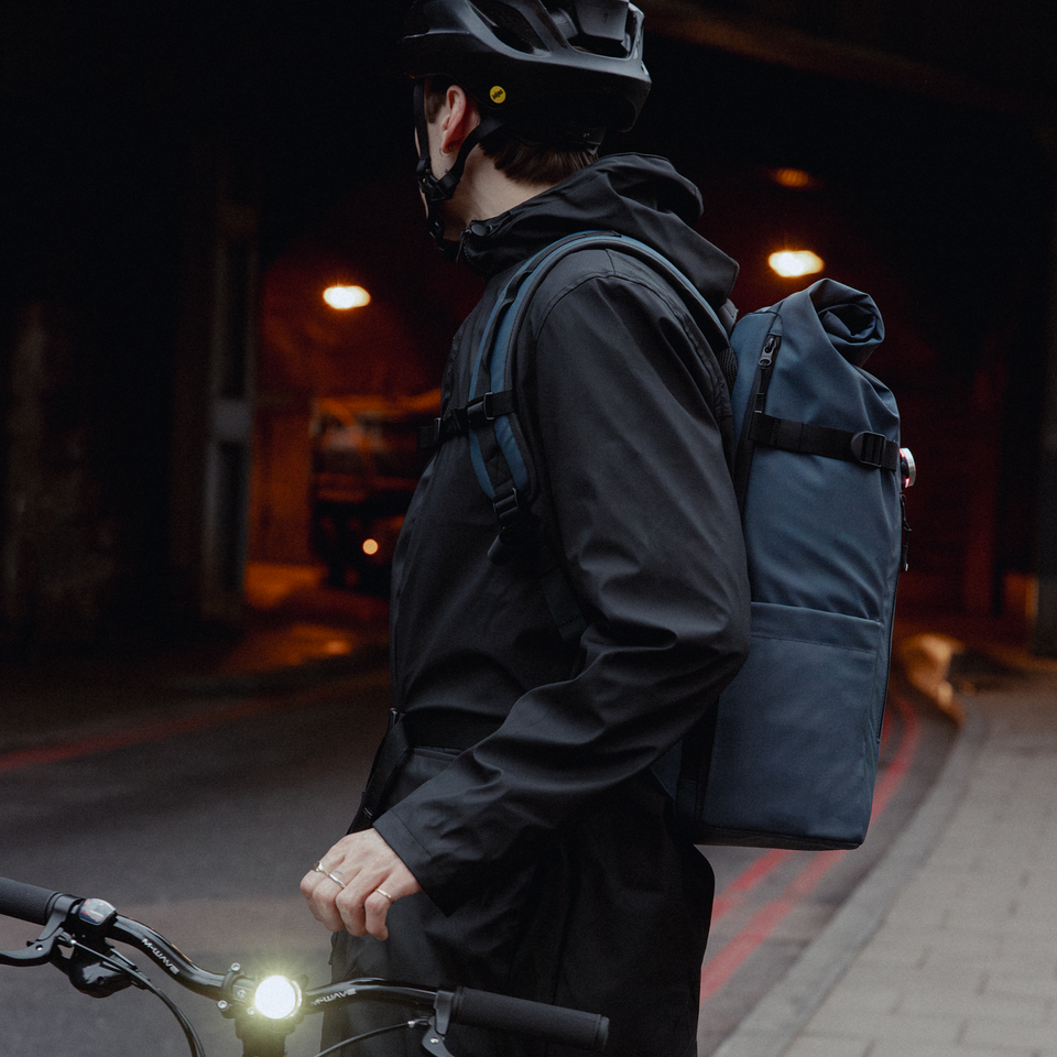 A man standing next to his bike with a Roll Top 30L in Tasmin Blue on his back