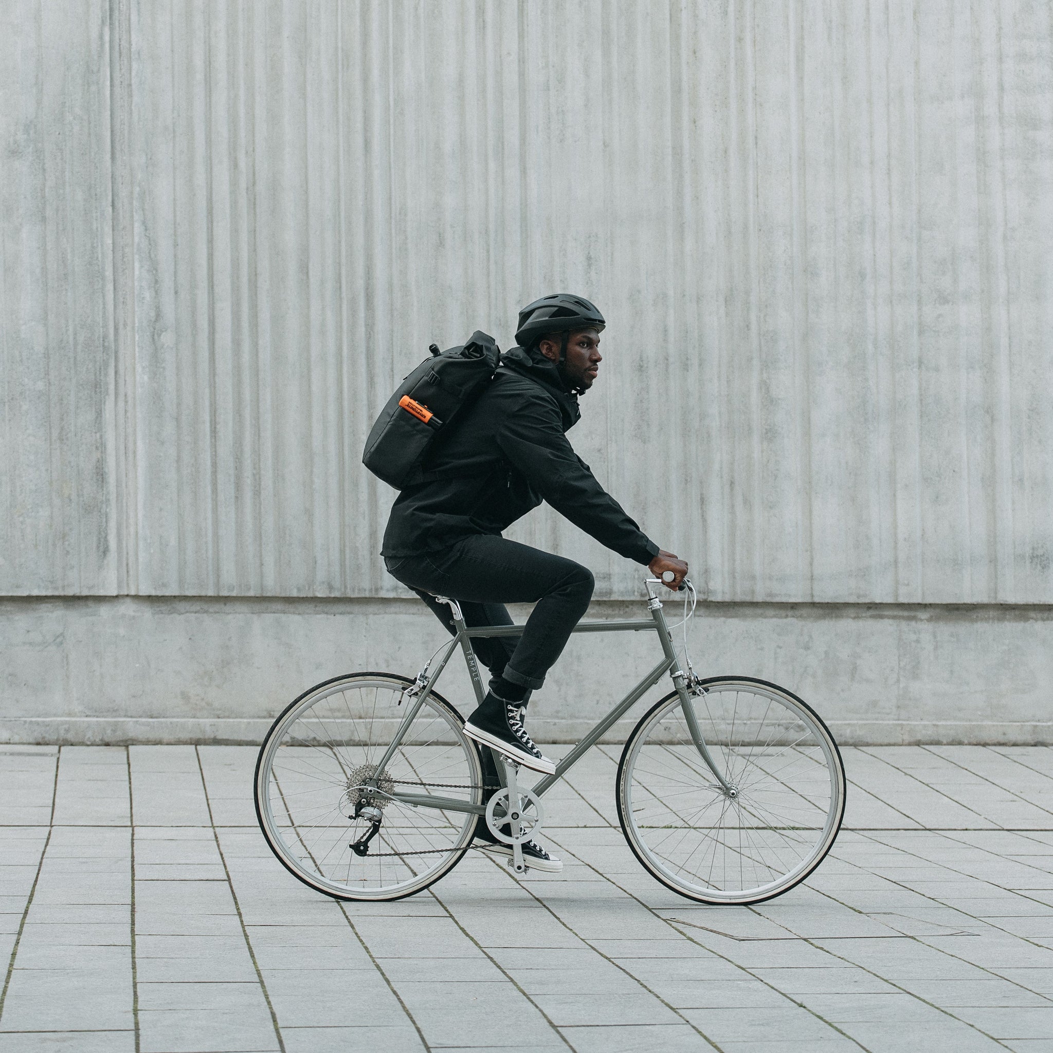 Side view of a man on a bike wearing The Roll Top in All Black.