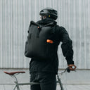 Man wearing Roll Top backpack in All Black on a bike