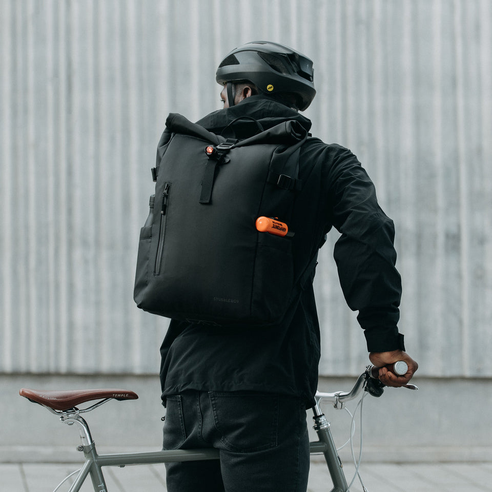 Man wearing Roll Top backpack in All Black on a bike