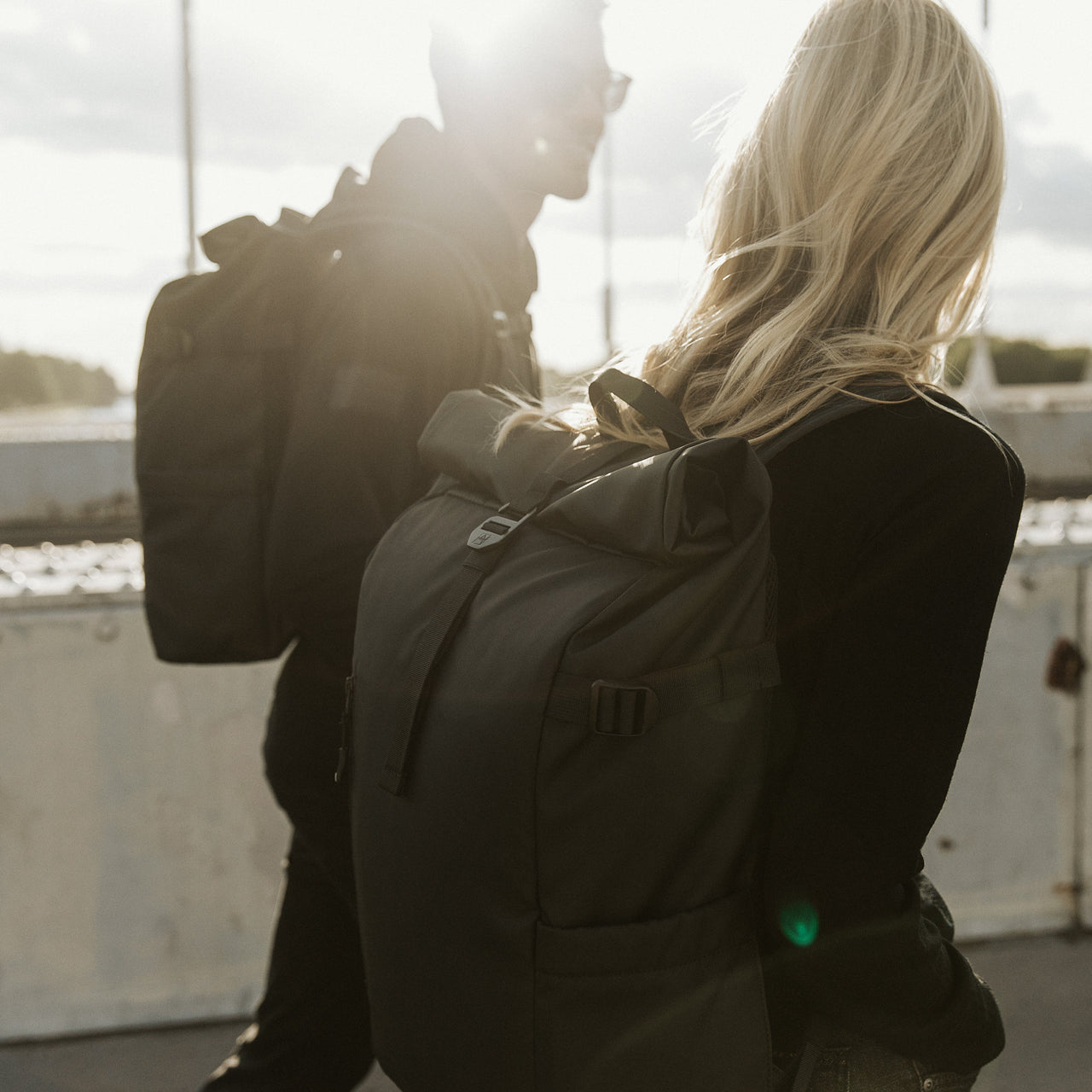 Man and women wearing Roll Top backpack in All Black