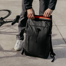 Man opening Roll Top backpack in All Black