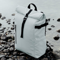 The Roll Top in Arctic White placed on pebbles by the sea.