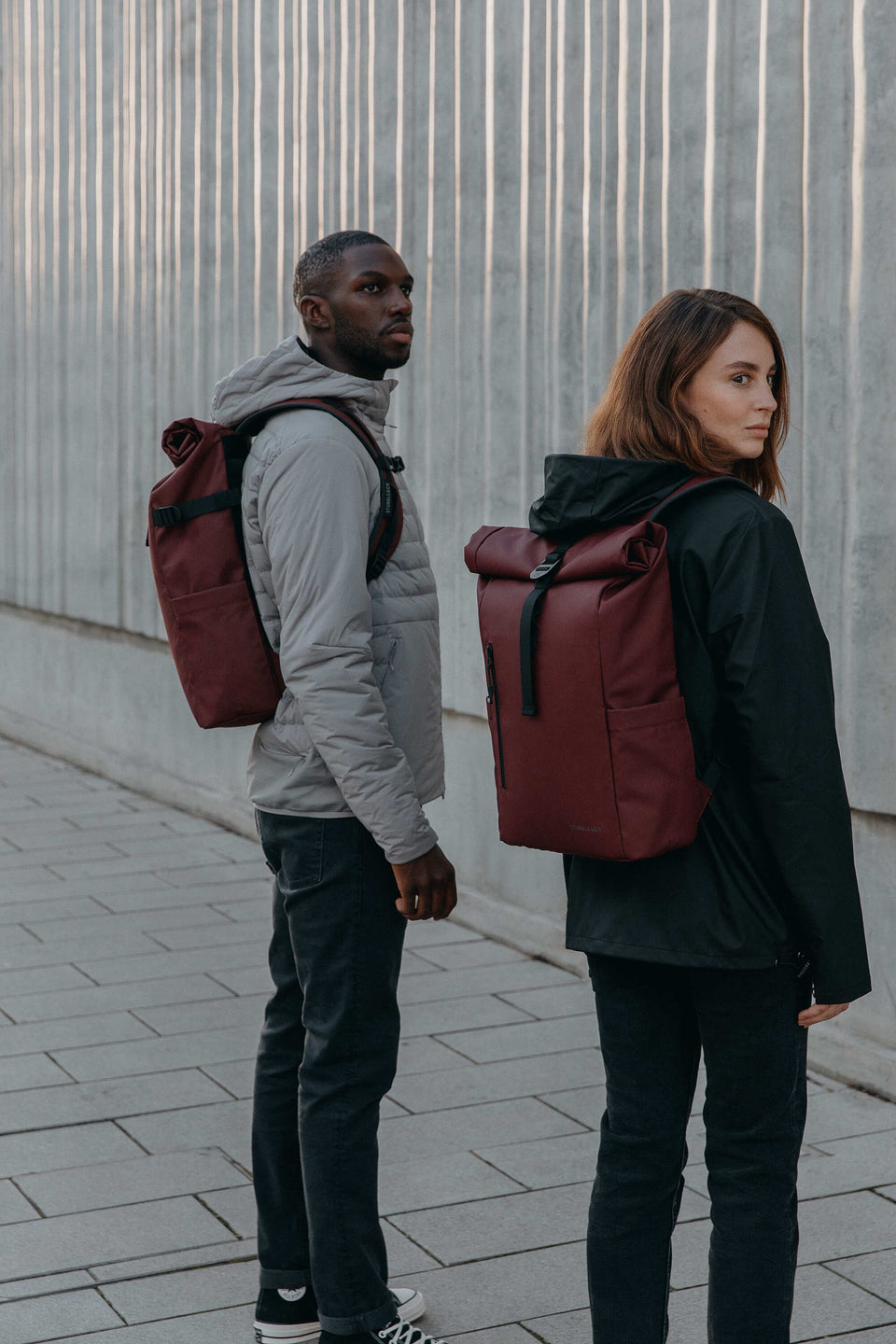 Man and women with Roll Top backpacks in red