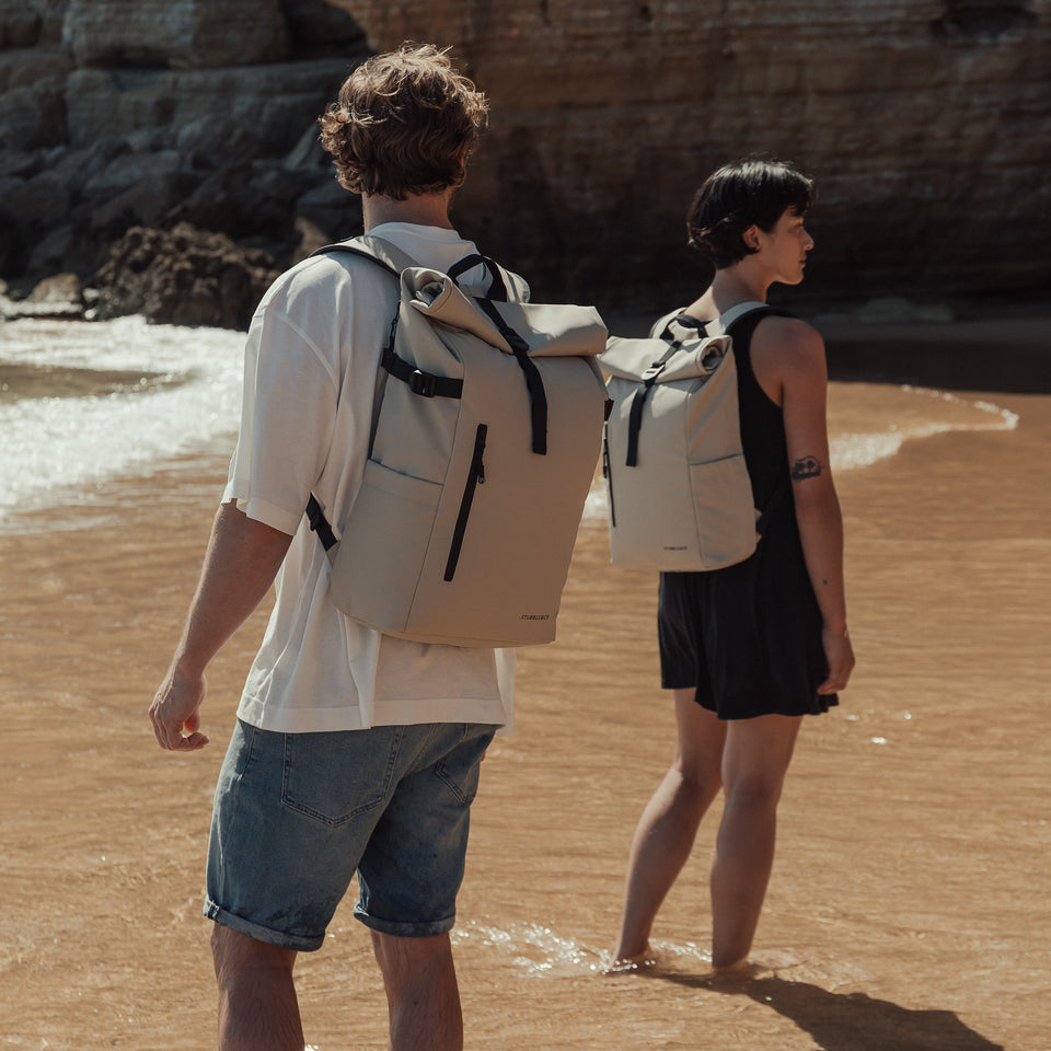 Two people with Roll Top backpack on a beach