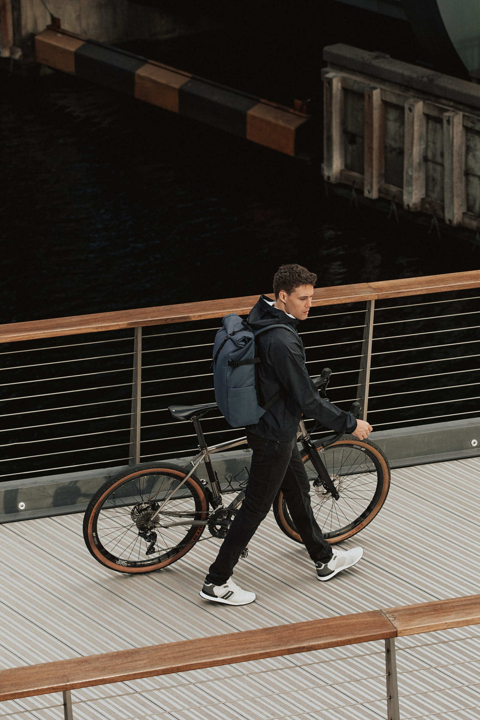 Man with bike and Roll Top backpack in blue