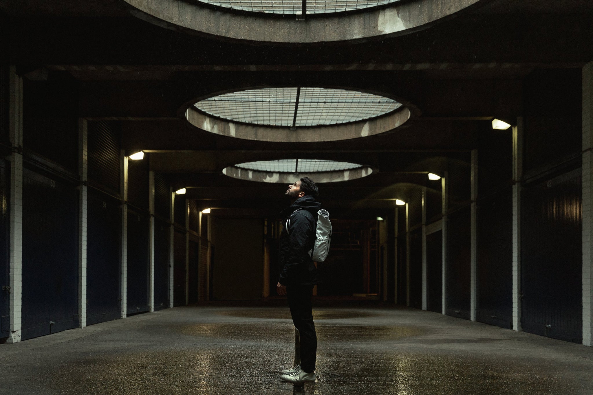 Man standing in open space with Roll Top Mini backpack